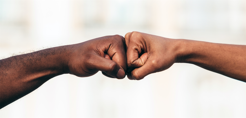 Dia Nacional da Consciência Negra propõe discussão sobre formas de combater o racismo Em uma foto com fundo desfocado e com tons claros, dois homens com a pele negra e a mão fechada ...